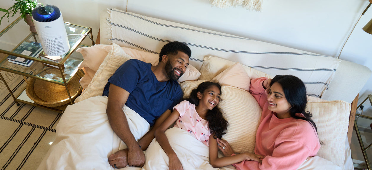 A family in bed next to an air purifier.