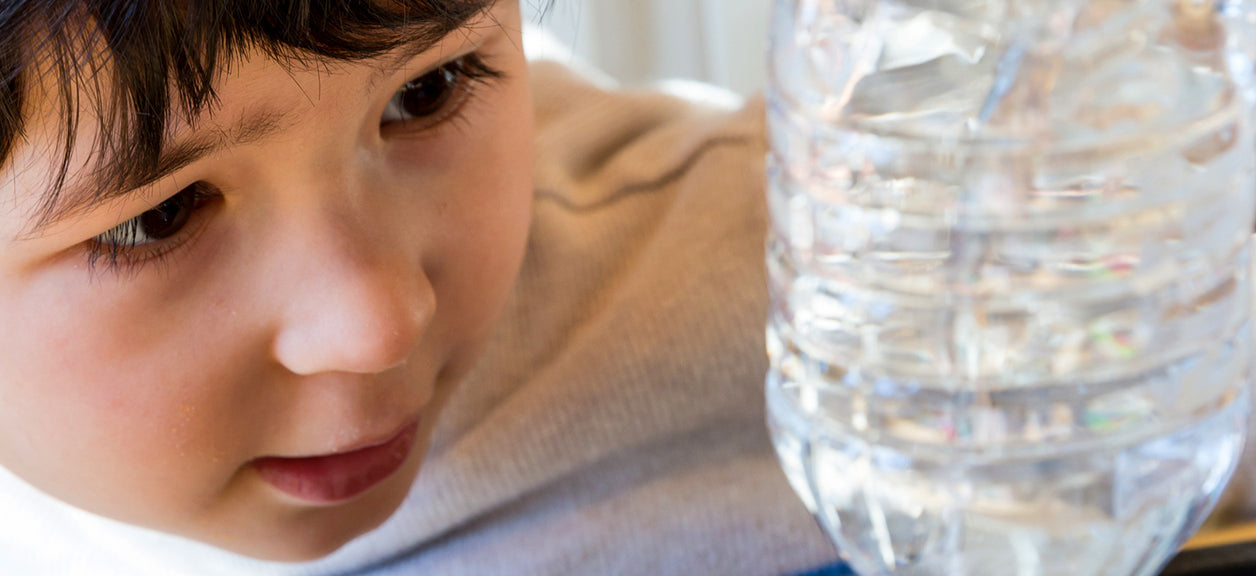 child looking at plastic water bottle