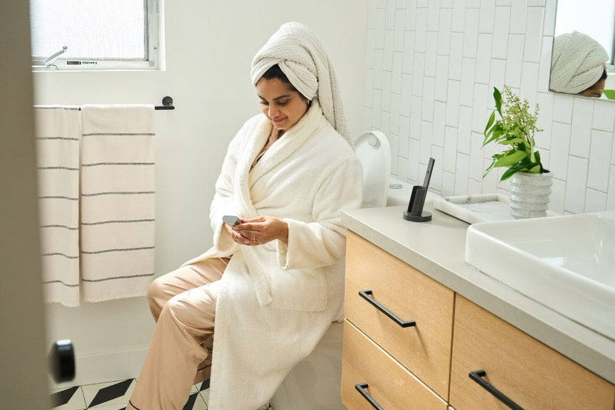 A woman in a bathroom sitting on a Bidetmega 500S