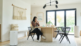 A woman with congestion sitting at a kitchen table.