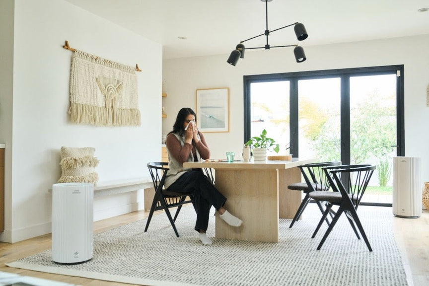 A woman with congestion sitting at a kitchen table.