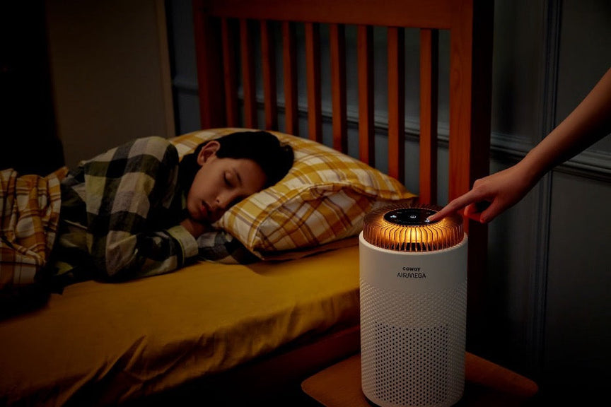 A bedroom with a sleeping child and an Airmega 50.