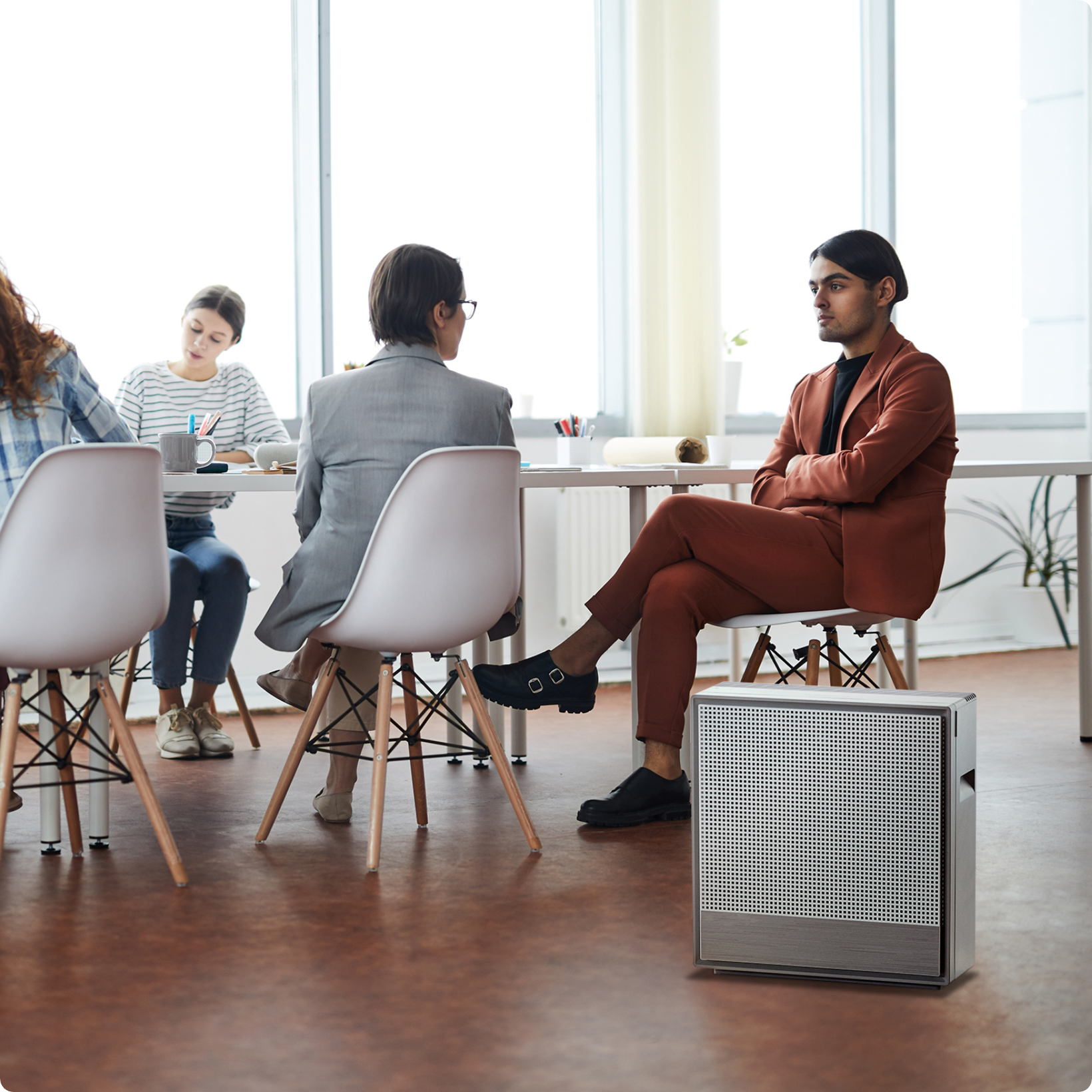 Workers sitting near desks in room with Airmega air purifier