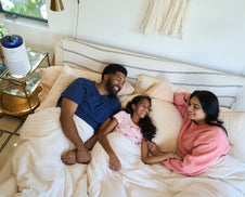 A family in bed next to an air purifier.