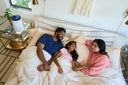 A family in bed next to an air purifier.