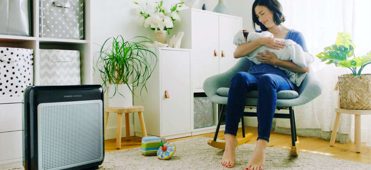 woman sitting on chair holding a baby in room with air purifier