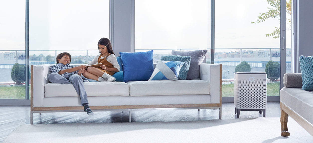 children sitting on couch next to air purifier