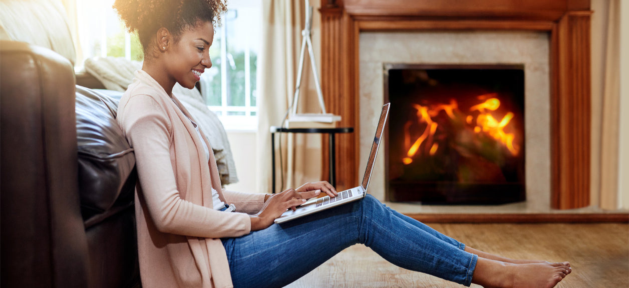 woman sitting by fireplace on laptop