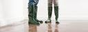 two people in boots standing in water