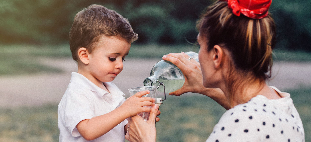 woman filling up childs glass with water