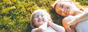 mother and child laying in the grass smiling