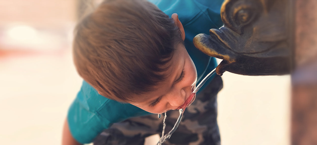 child drinking water from spout