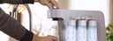 hands filling water bottle from coway aquamega 