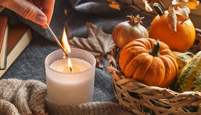 A person lighting autumn candles in their home.