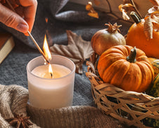 A person lighting autumn candles in their home.