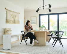 A woman with congestion sitting at a kitchen table.