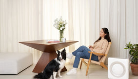 A person with her dog beside an Airmega Mighty AP-1512HH air purifier.