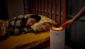 A bedroom with a sleeping child and an Airmega 50.