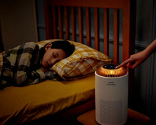 A bedroom with a sleeping child and an Airmega 50.