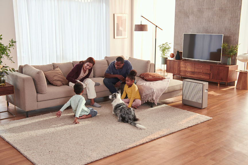 A family playing with their dog in a living room near an Airmega 250.