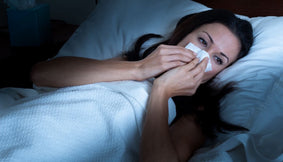 A woman with a stuffy nose in bed.