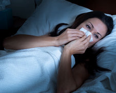 A woman with a stuffy nose in bed.