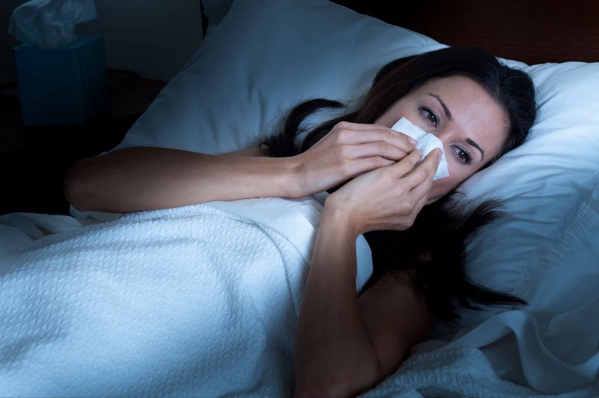 A woman with a stuffy nose in bed.