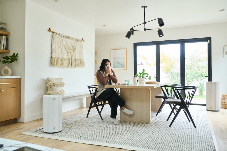 A woman blowing into a tissue in her living room.