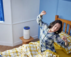 A person waking up in their bedroom in the morning with the Airmega 50.